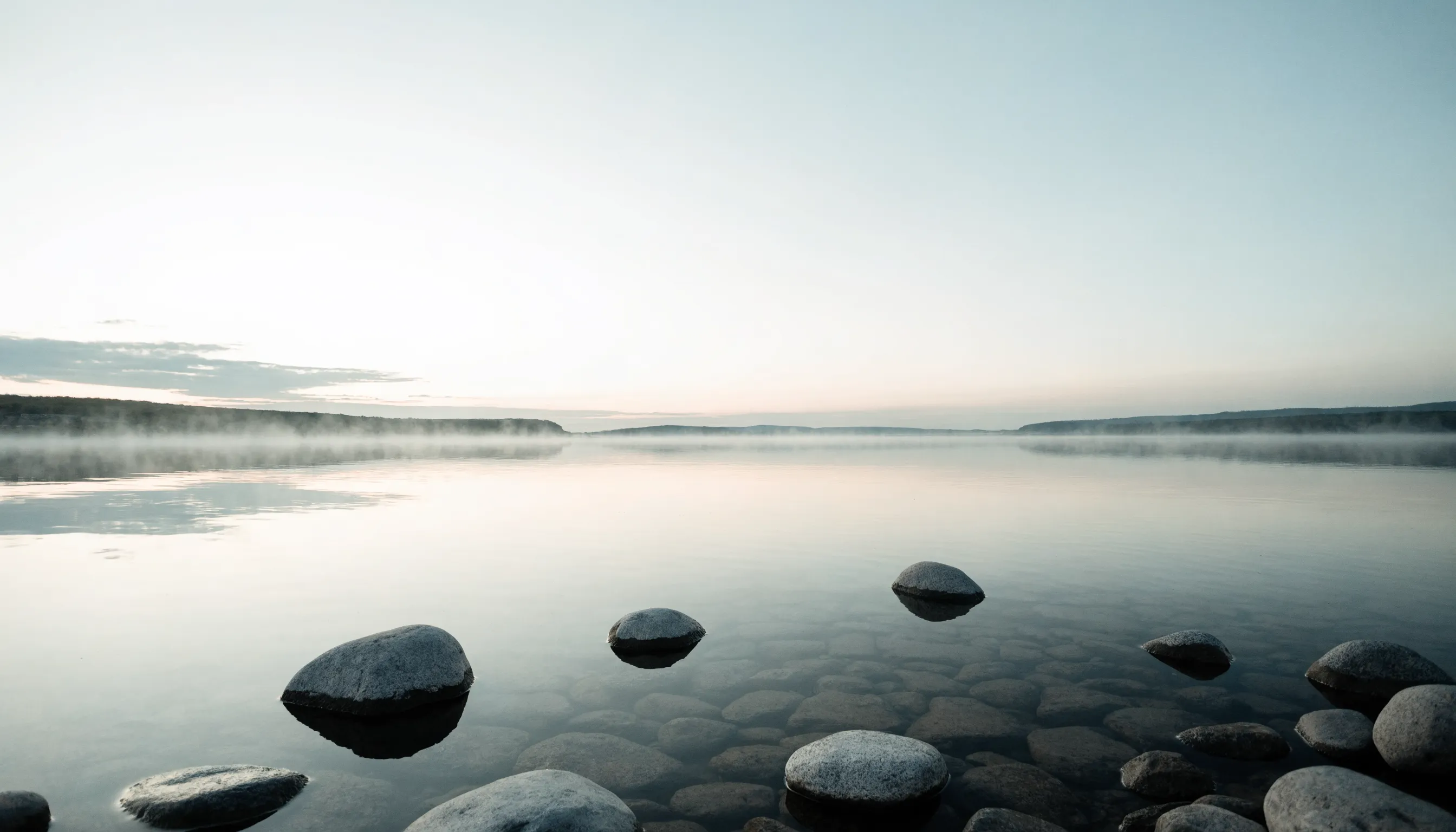 Stilla sjö i gryningsdimma